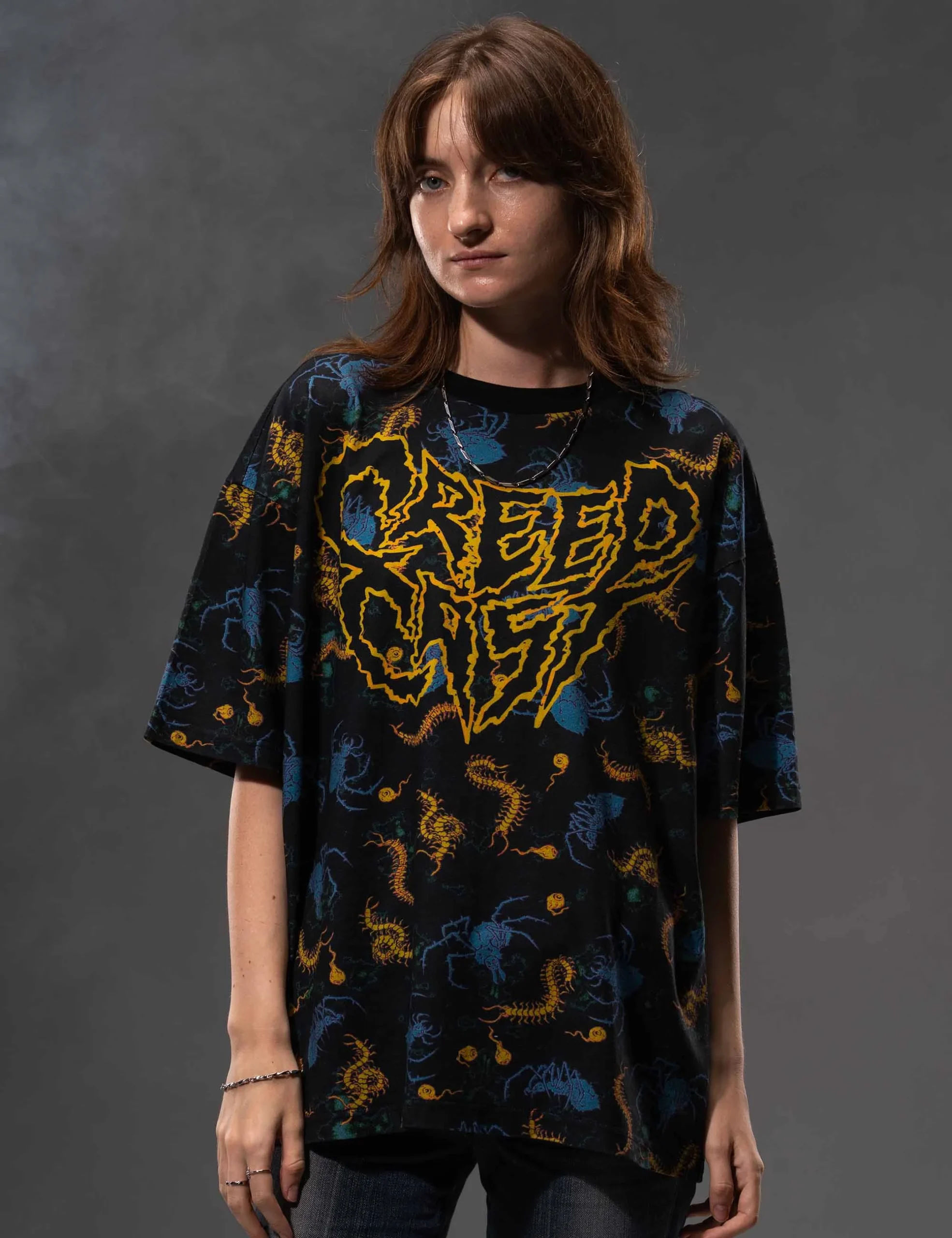 Angled laydown showcasing garment drape and sleeve finishing on the Creepy Crawlies Oversized Tshirt - Creep Cast Merch